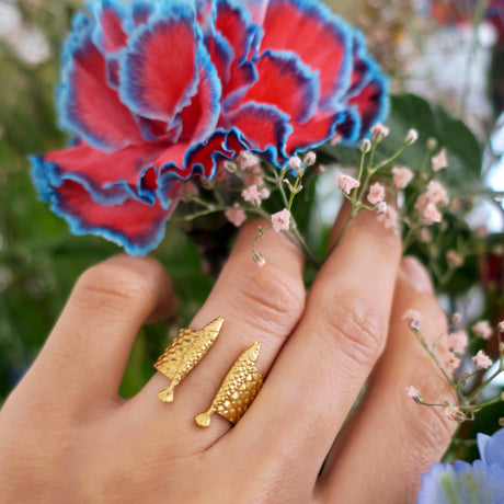 Double fish ring in 18K gold-plated silver 925 worn on finger, styled with carnation flowers