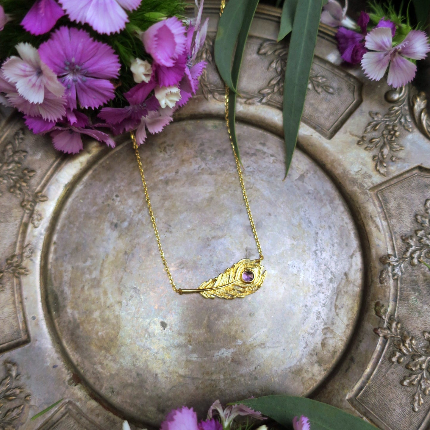 Peacock feather amethyst necklace styled with pink dianthus flowers on an antique silver tray