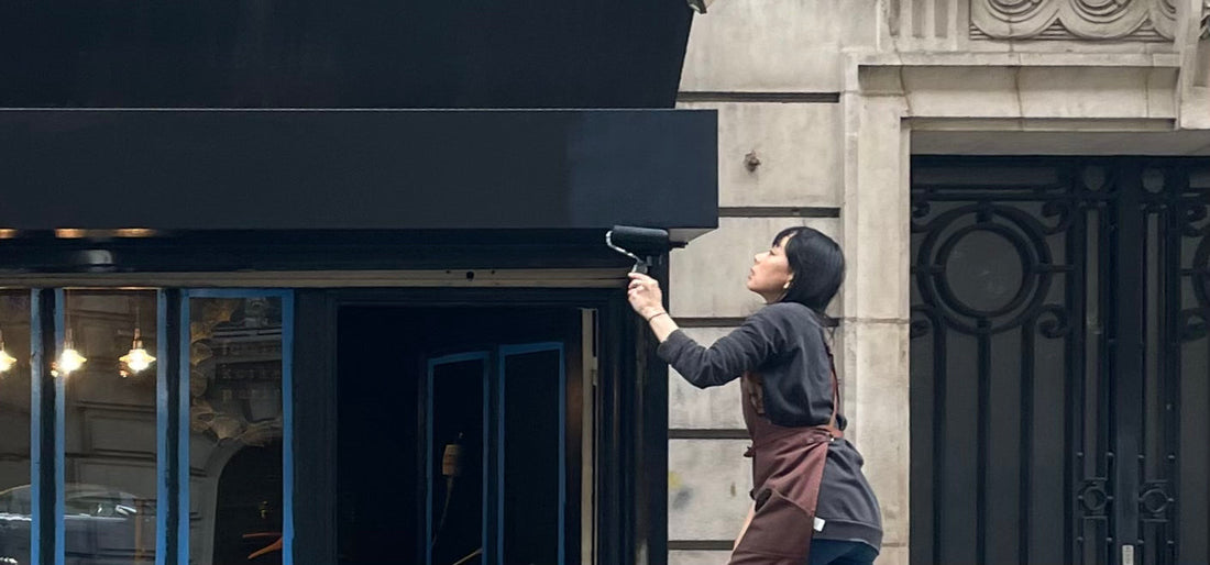 Fusako Koike painting the storefront of her Montmartre jewelry atelier — the beginning of her handcrafted silver and gold-plated creations in Paris.