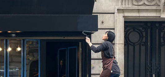 Fusako Koike painting the storefront of her Montmartre jewelry atelier — the beginning of her handcrafted silver and gold-plated creations in Paris.