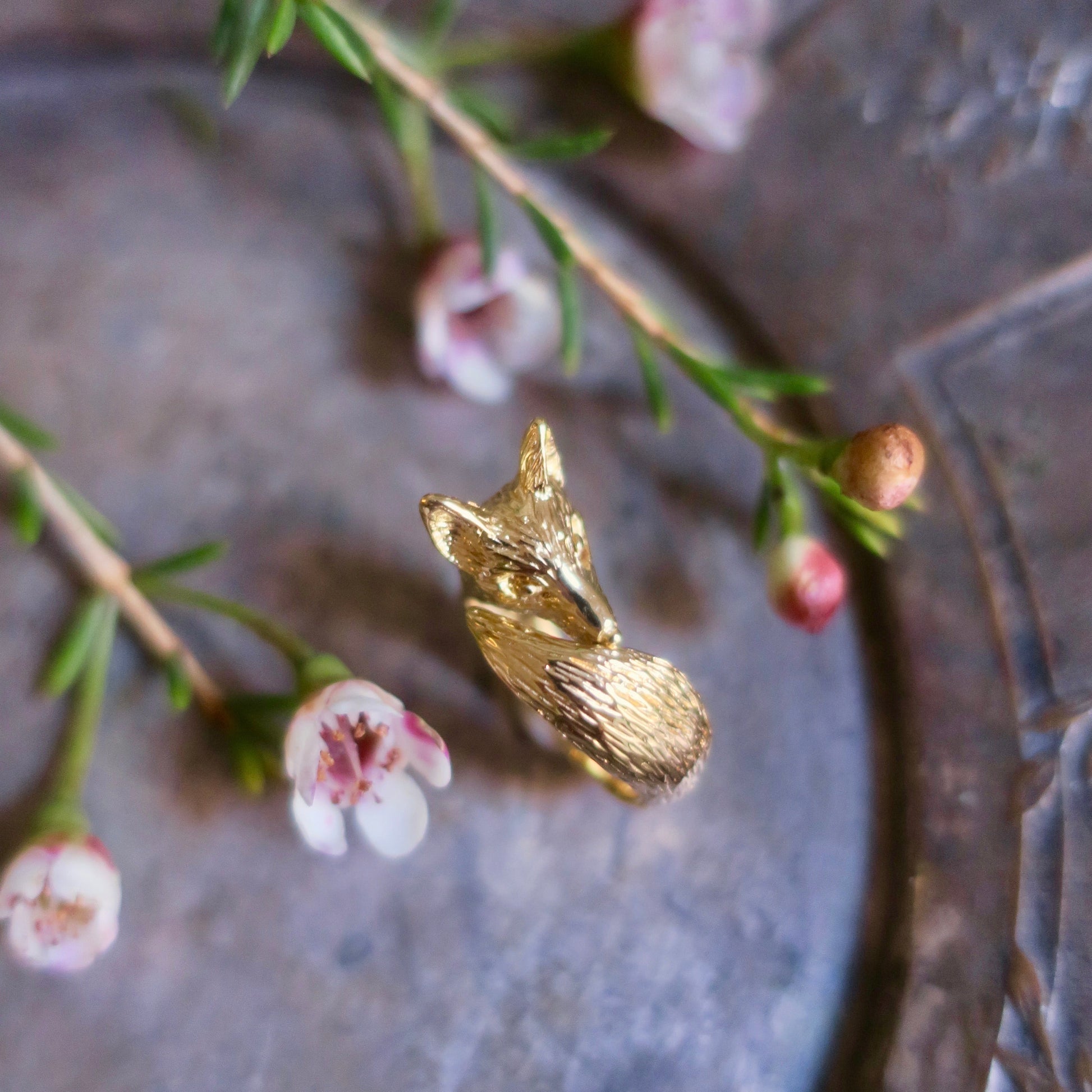 Fox pinky ring in 18K gold-plated sterling silver displayed on a vintage tray with flowers, highlighting its small size, textured fur, and artisan craftsmanship from Paris