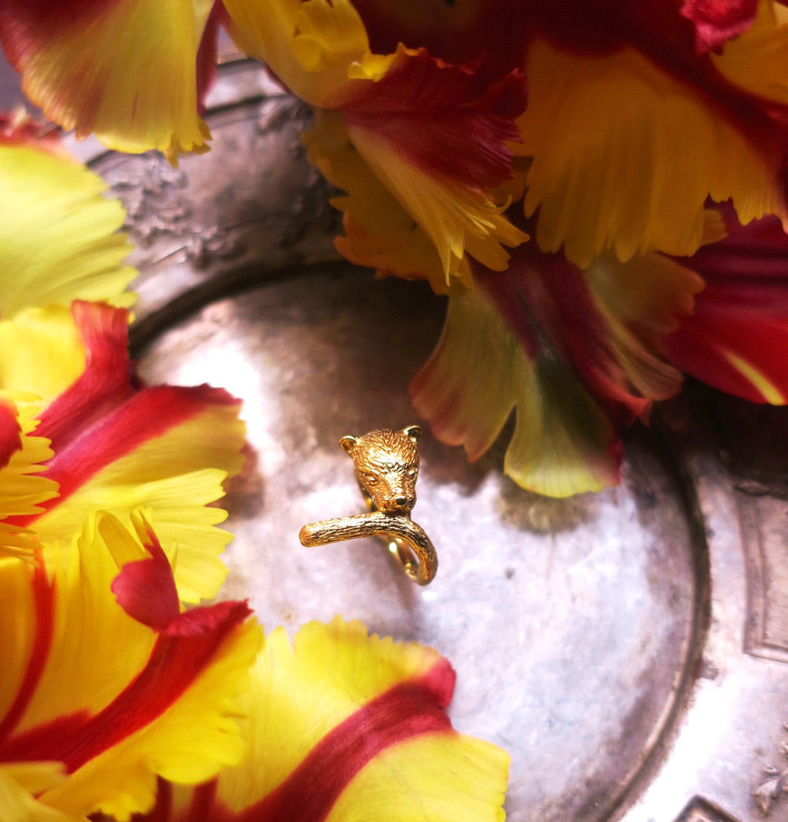Gold-plated silver panther ring displayed among vibrant yellow and red flowers – handcrafted animal jewelry from Paris, symbol of strength and elegance.
