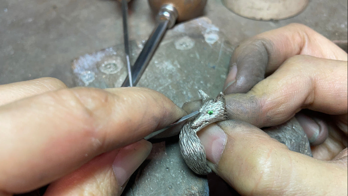 Hand-sculpting a sterling silver fox ring with green gemstone eyes in a Montmartre Paris atelier workshop