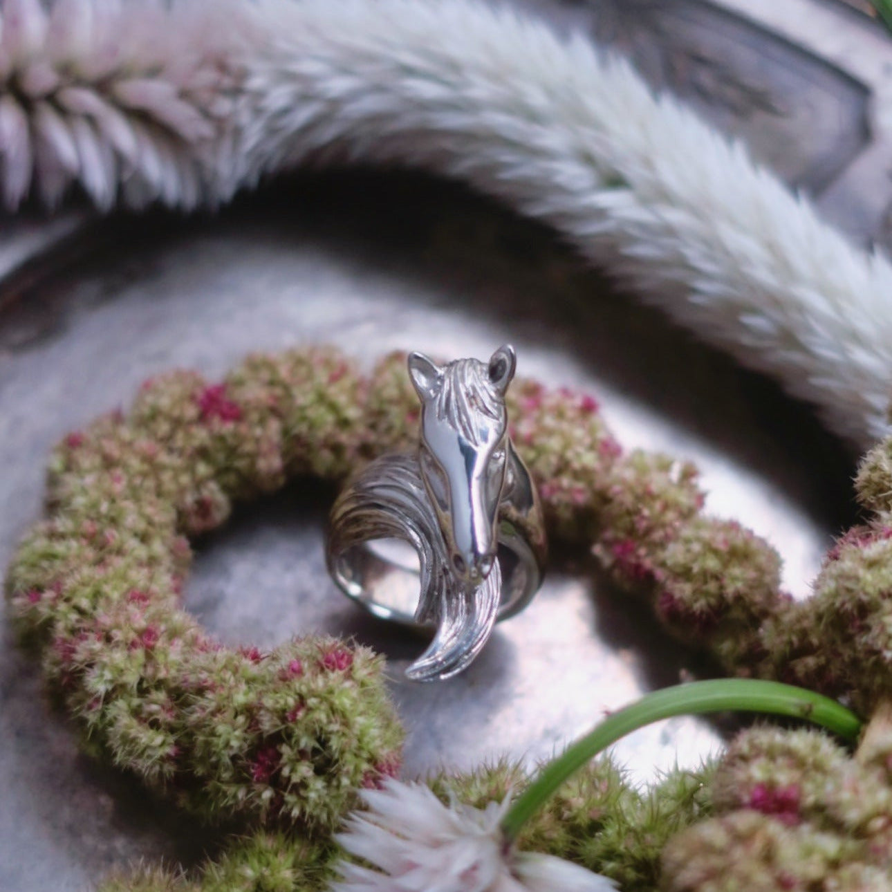 Silver horse ring styled in a natural setting, highlighting its reflective surface, organic lines and Parisian hand-crafted animal jewellery aesthetic.