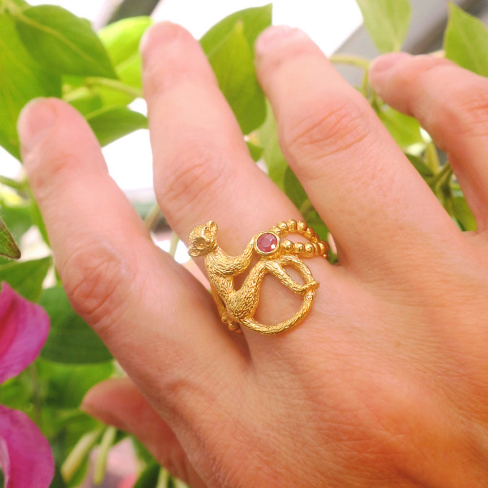 Hand wearing an 18K gold-plated silver 925 monkey ring with opaque rough-cut ruby