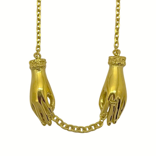 Gold-plated sterling silver hand necklace featuring two sculpted hands holding an antique-style chain. Artisan jewelry handmade in Paris.