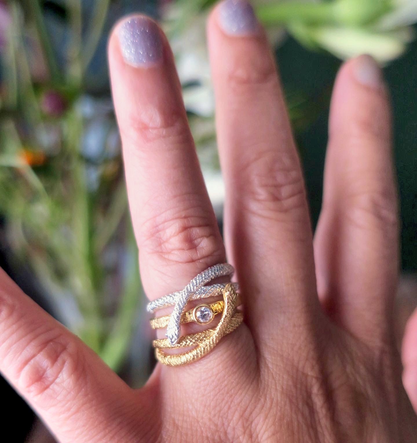 Close-up of mixed-metal snake wrap ring in sterling silver and gold-plated silver worn stacked with a solitaire ring — original animal-inspired (animalière) jewellery by an artisan bijoutière in Paris.