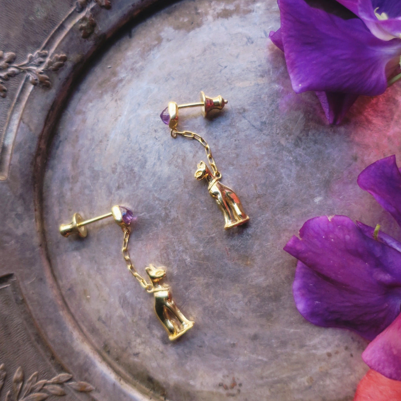 18K gold-plated silver 925 Egyptian cat earrings styled on an antique tray with purple flowers