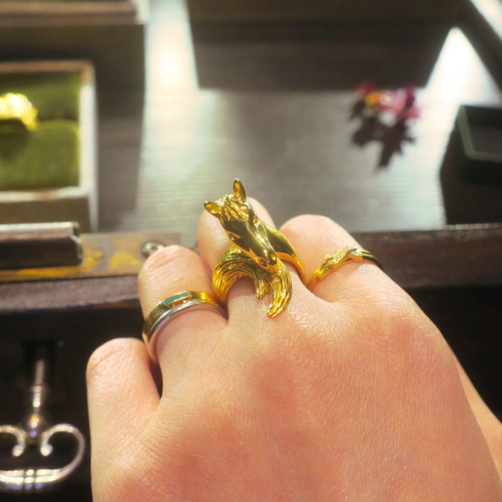 Hand wearing an 18K gold-plated silver 925 horse ring, showing the sculpted horse head and curved tail detail