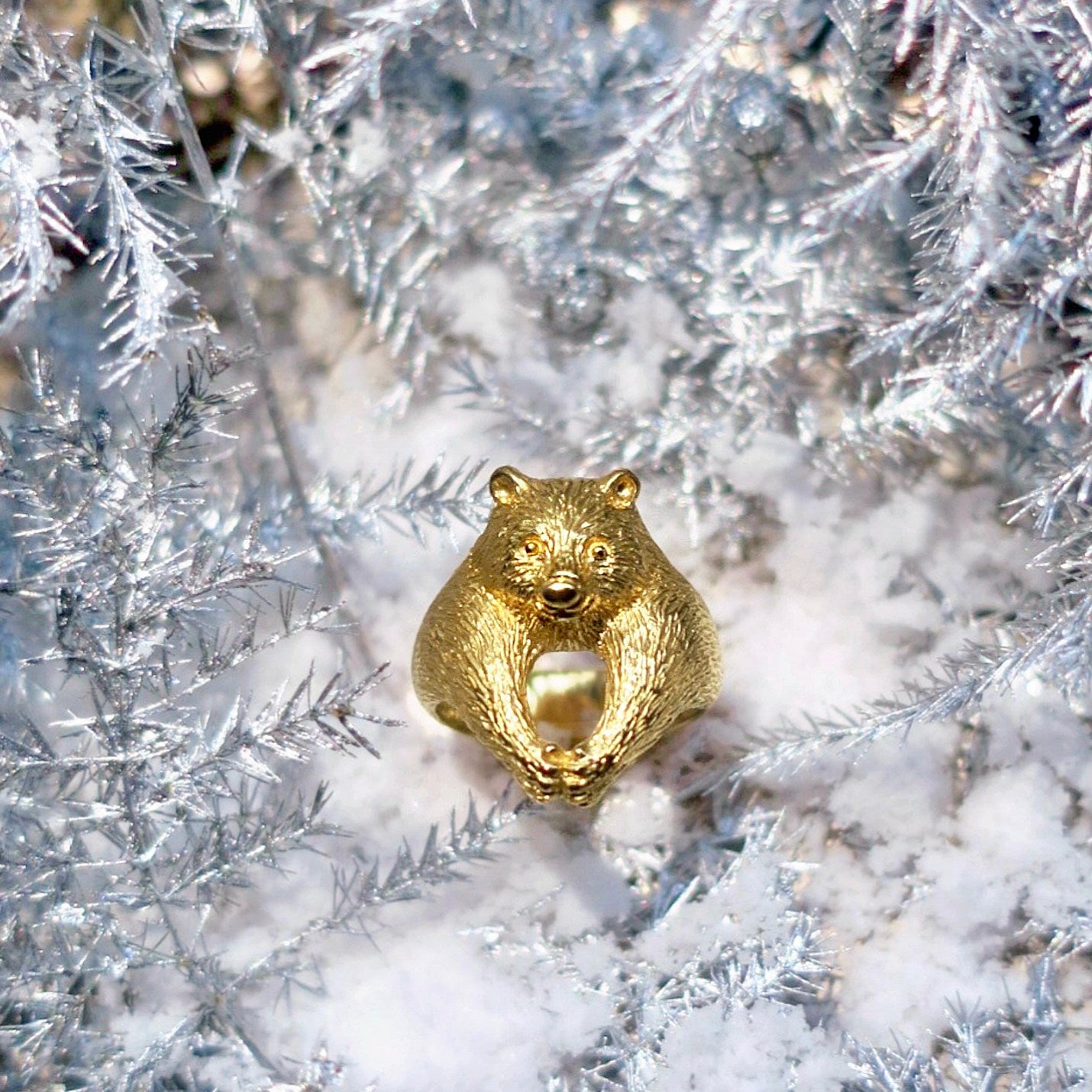 Bear ring in 18K gold-plated silver 925 photographed on snow, front view with clasped paws and softly sculpted face