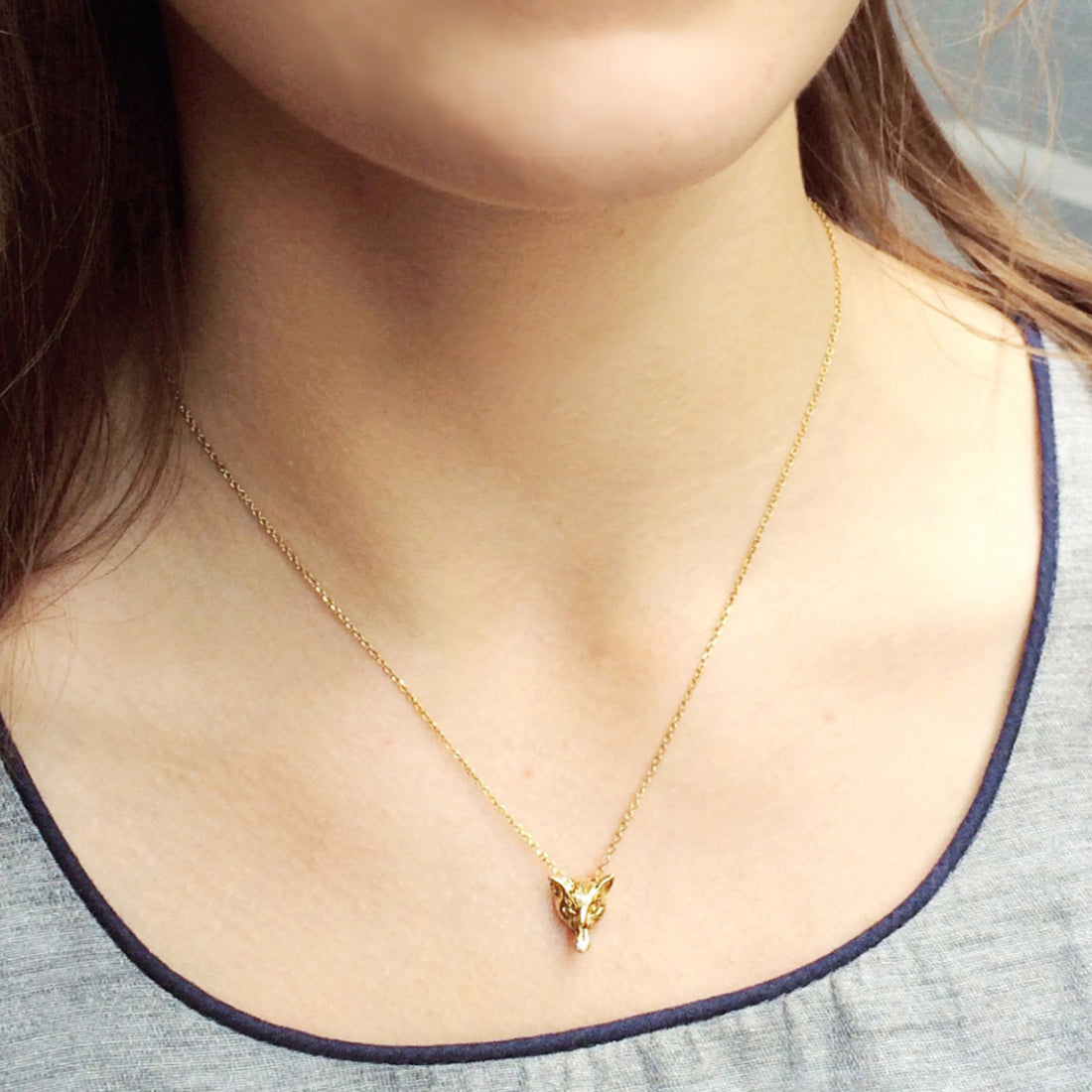 Cat pendant necklace worn on the neck, hand-sculpted in 18K gold-plated silver, showing the playful ‘langue de chat’ tongue detail. Paris artisan animal jewelry lifestyle shot.