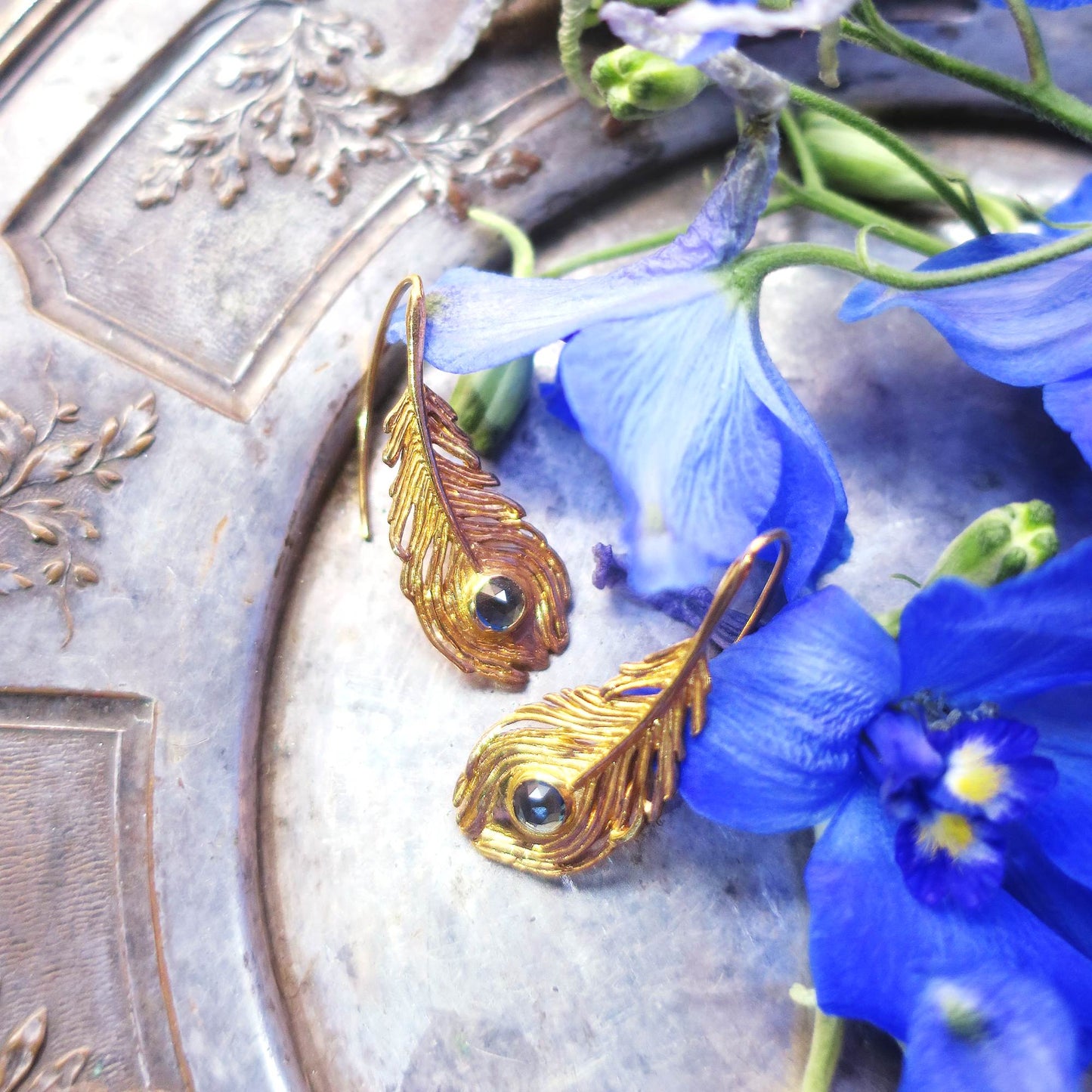 Peacock feather blue topaz earrings styled on an antique silver tray with bleu flowers