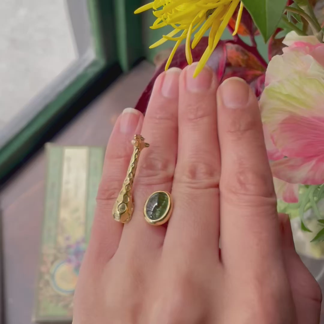 Giraffe ring worn on finger, gold-plated silver with green tourmaline, showing volume and sculptural depth in motion