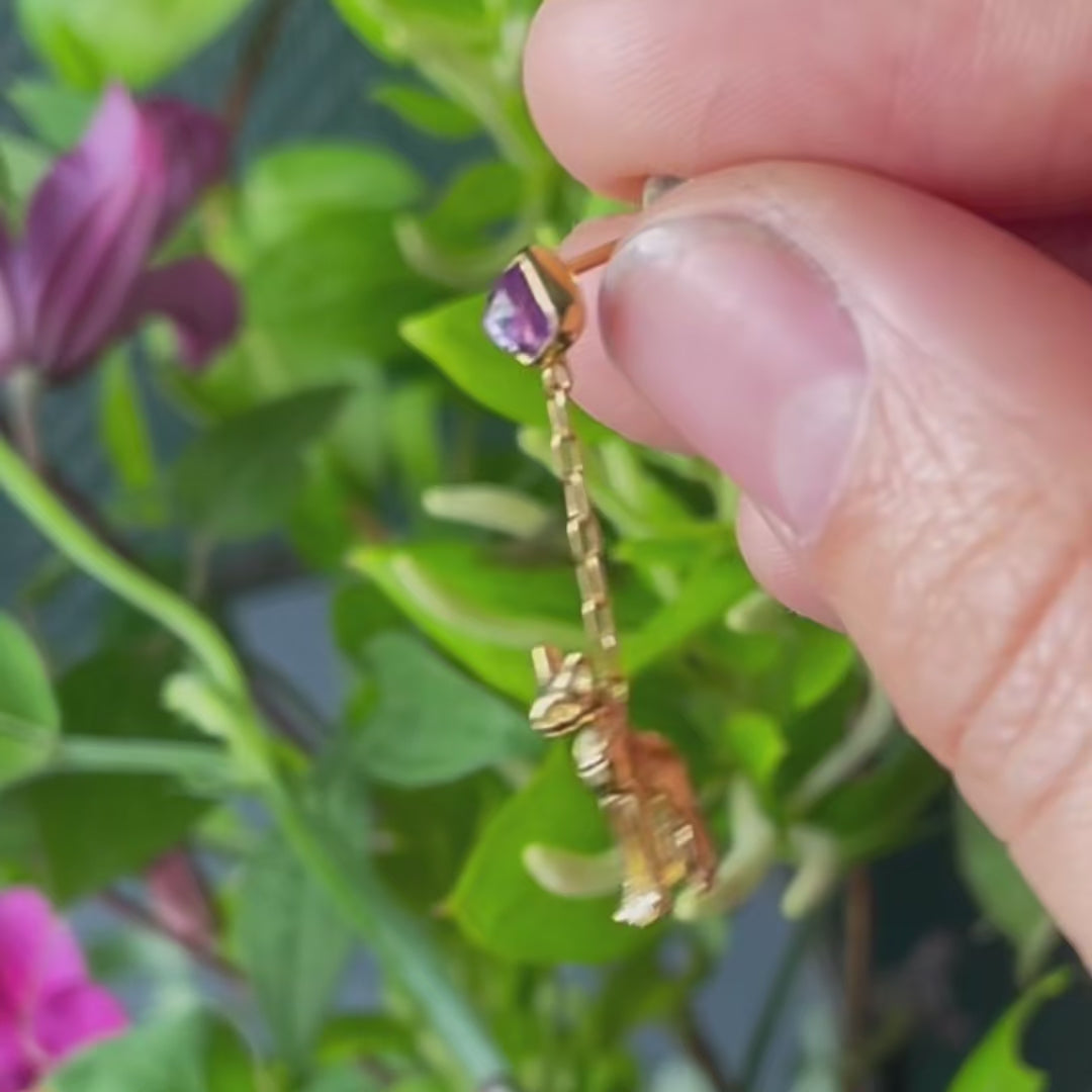 Video of one Egyptian cat earring held between fingers, moving to show both sides and the gentle swing of the chain