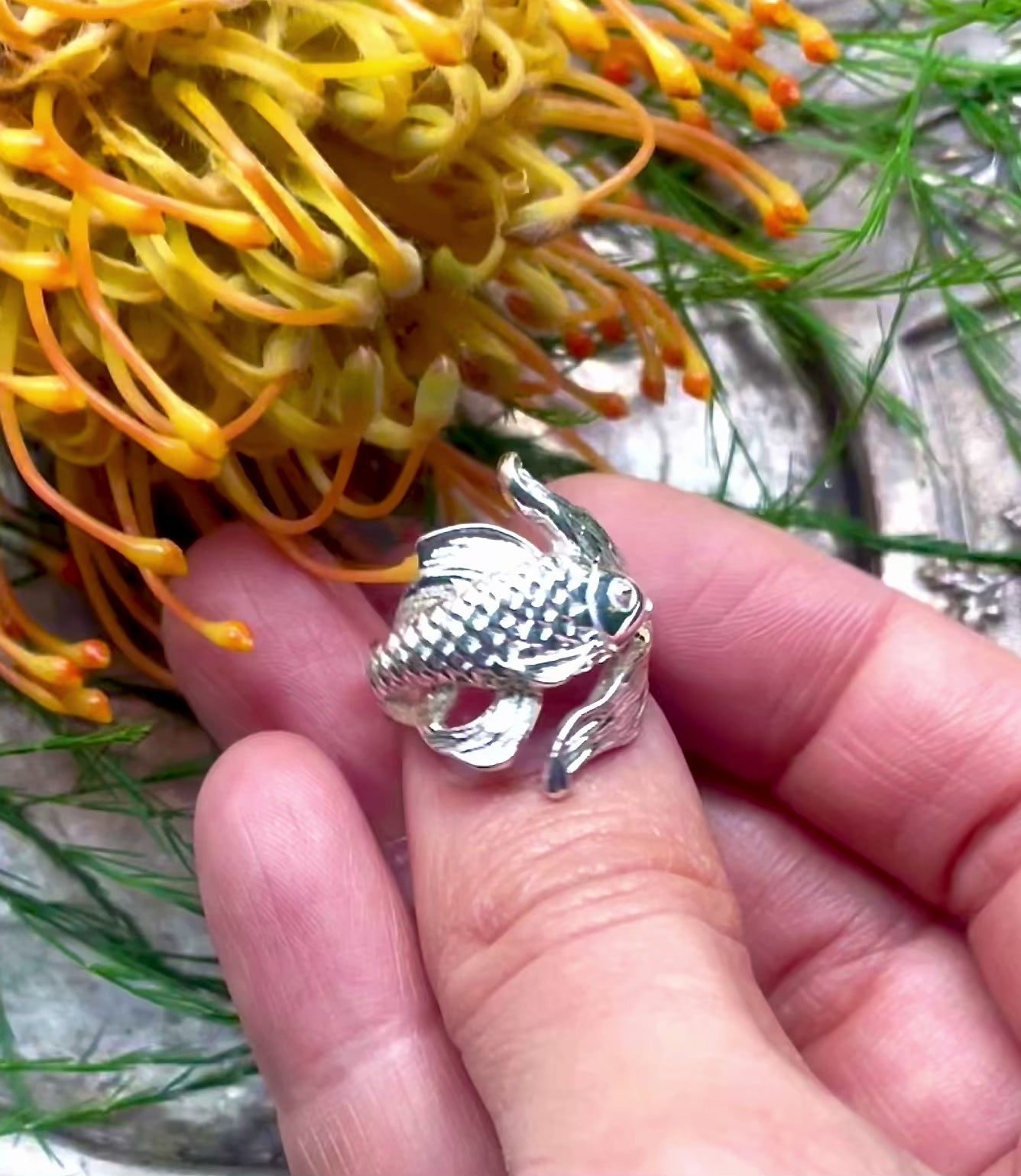 Detail of carved silver goldfish ring in video.