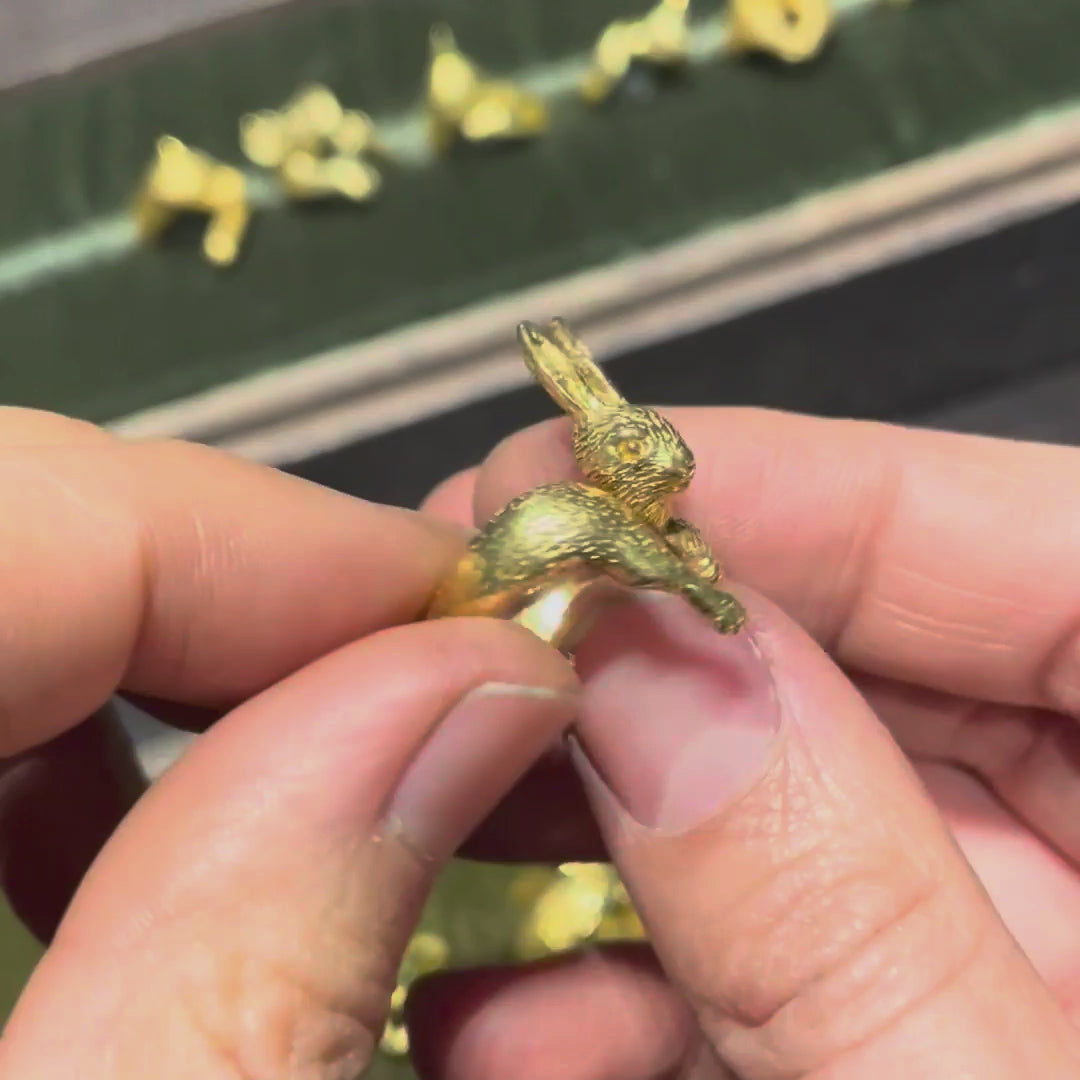 Hand holding a gold-plated silver rabbit ring, rotating to reveal finely sculpted facial expression and detailed animal features