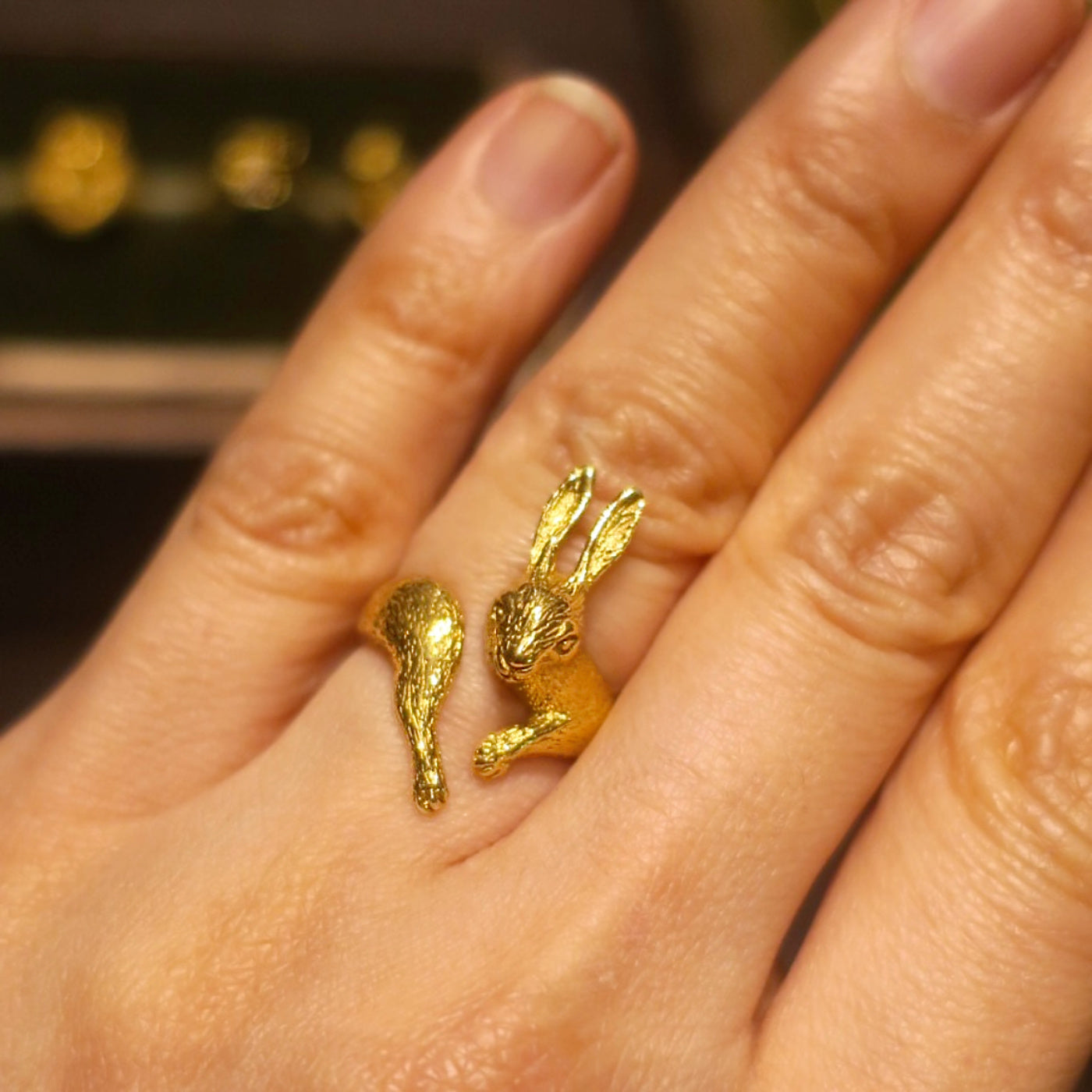 Gold-plated silver rabbit ring worn on finger, sculpted animal design with finely detailed facial expression and textured surface