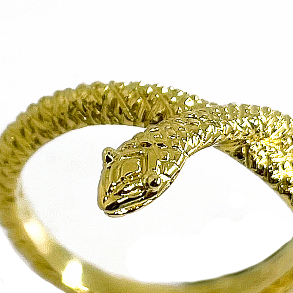 Close-up of hand-carved snake ring in gold-plated silver 925, showing engraved scales, eyes, and serpent head detail