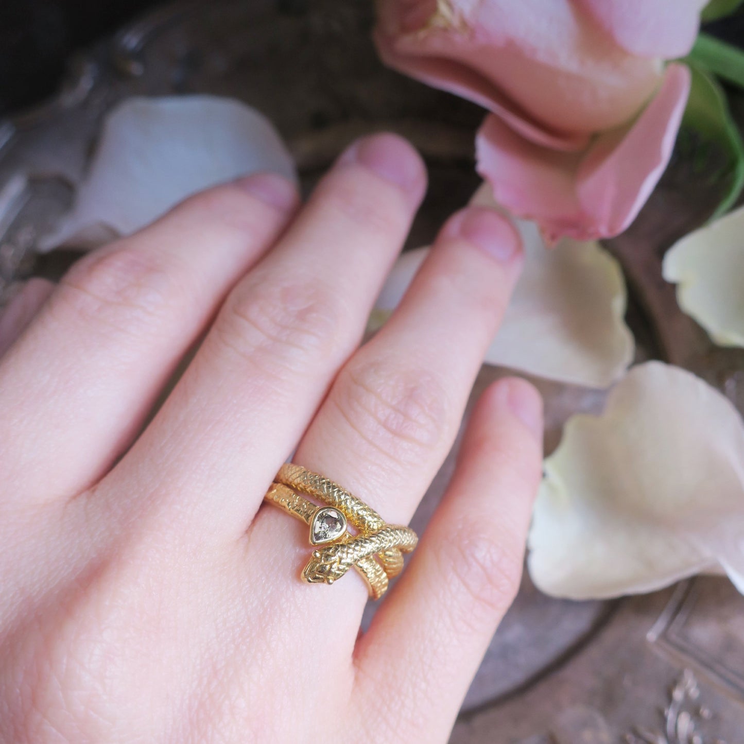Snake ring in gold plated sterling silver stacked with white sapphire ring on finger