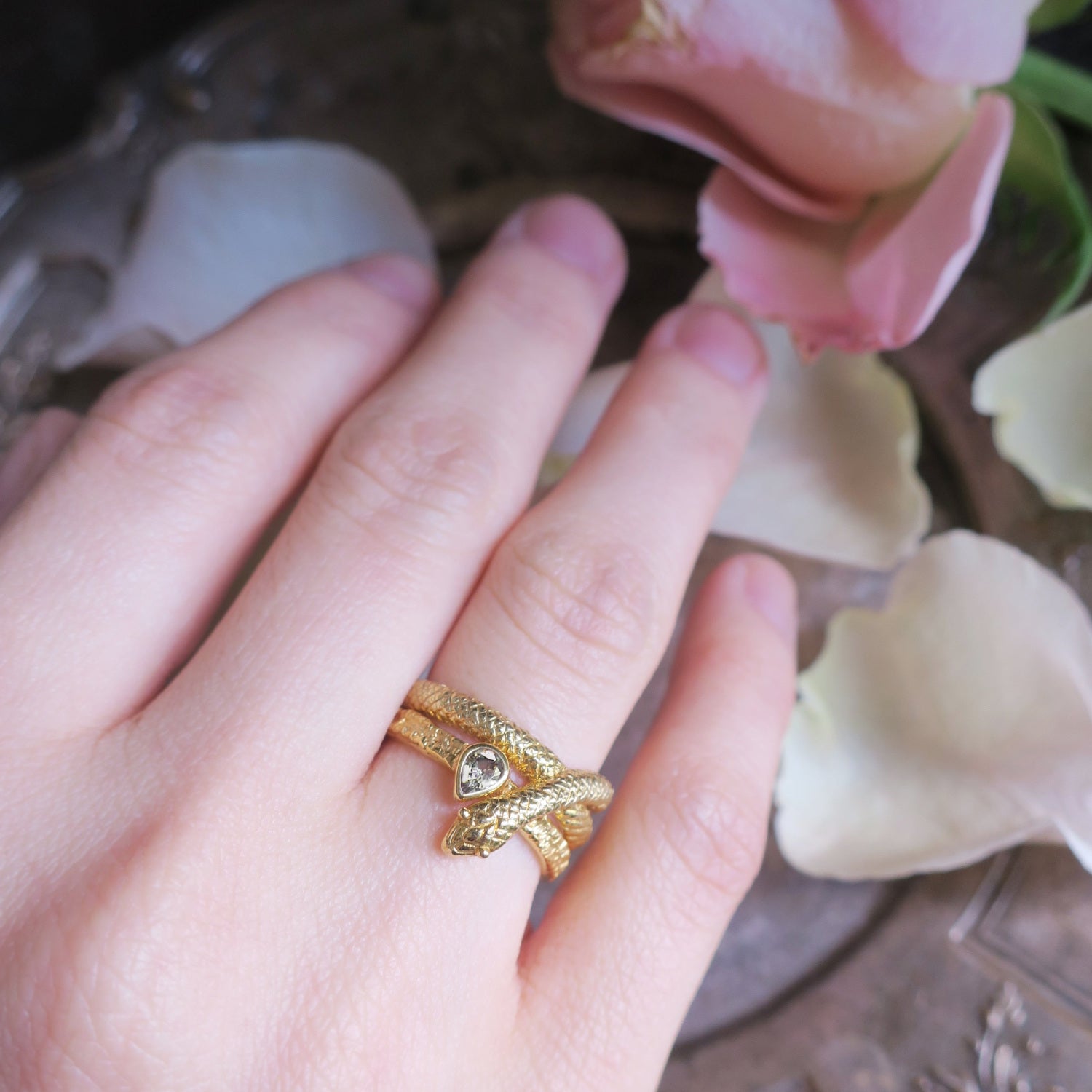 Snake ring in gold plated sterling silver stacked with white sapphire ring on finger